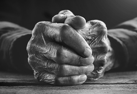 The weathered, clasped hands of a longtime tradesman