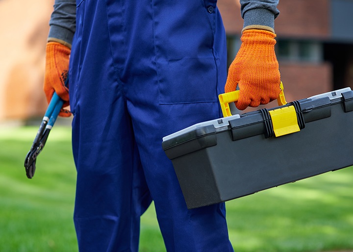 A home-service technician carrying a toolbox to a job
